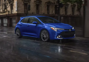 A blue 2023 Corolla Hatchback driving down a street near Noblesville, Indiana