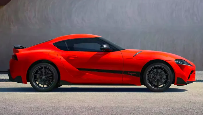 A red 2024 GR-Supra parked in front of a grey concrete wall, photographed from the side near Noblesville, IN