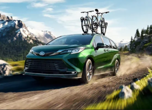 A green 2024 Toyota Sienna driving down a dirt road with a bicycle attached to the roof near Noblesville, Indiana