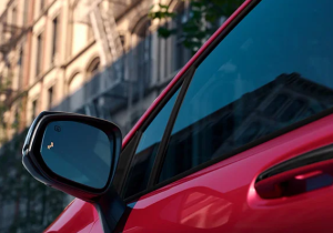 A red 2025 Toyota Sienna photographed from up-close near the mirror, parked in front of a city building near Noblesville, Indiana