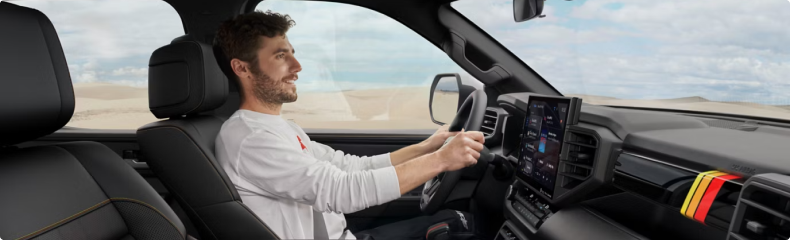 Smiling driver behind the wheel of a Toyota truck with TRD stripes on the dashboard