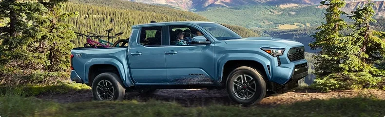 Blue Toyota Tacoma Double Cab carrying mountain bikes on a forested mountain trail