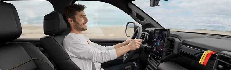 Smiling driver at the wheel of a Toyota truck beside its large center touchscreen