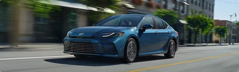 Blue 2026 Toyota Camry driving down a city street