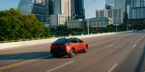 Red 2026 Toyota C-HR XSE AWD driving on a city highway, rear three-quarter view