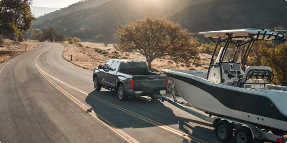 2026 Toyota Tundra CrewMax towing a boat on a winding road