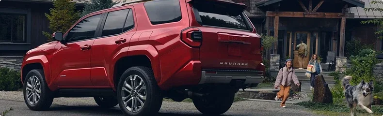 Red Toyota 4Runner with its tailgate open outside a house as a family and their dog walk up