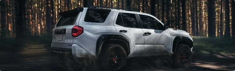 White TRD Pro 4Runner with a roof rack moving at speed along a forest track