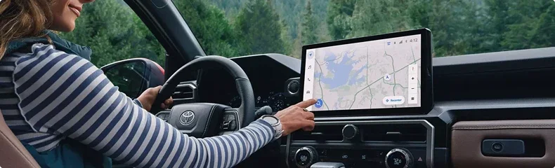 Driver reaching to the 4Runner touchscreen while it displays a navigation map