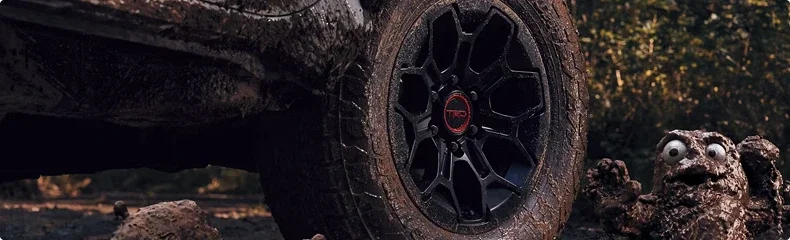 Close-up of a mud-caked black TRD alloy wheel and all-terrain tire on a 4Runner