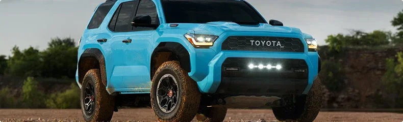 Bright blue TRD Pro 4Runner with a light bar and all-terrain tires on open ground