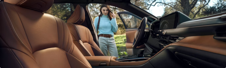 Crown Signia interior in tan leather, looking across the front seats to a woman opening the door