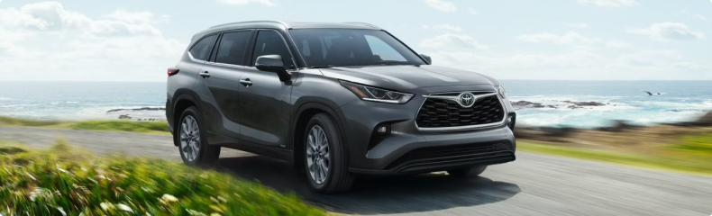 Gray Toyota Highlander on a coastal road with the ocean behind it