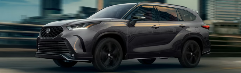 Dark gray Toyota Highlander XSE moving through a city at dusk