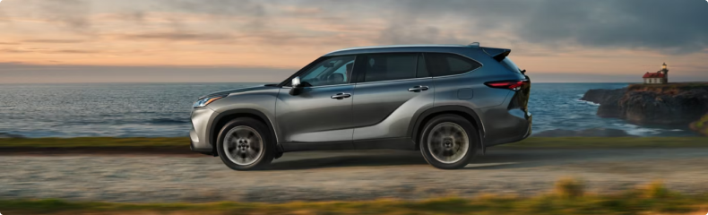 Silver Toyota Highlander in profile on a coastal road at dusk