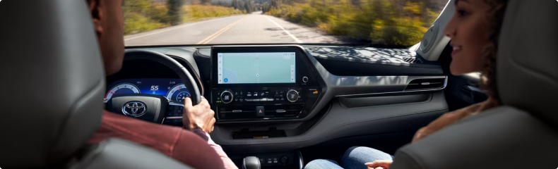 View from the Highlander back seat toward the dashboard as it travels a tree-lined road