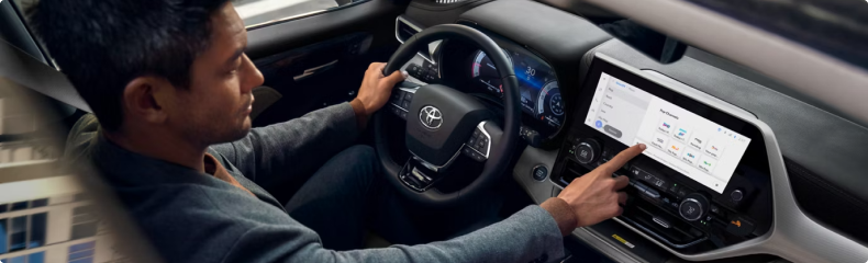 Driver reaching to the Highlander touchscreen while holding the steering wheel