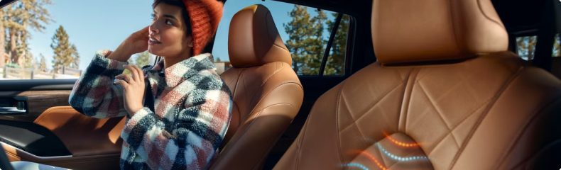 Toyota Highlander interior in tan leather, looking past the front seats to a passenger in the second row