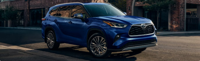 Blue Toyota Highlander parked on a city street outside a brick building