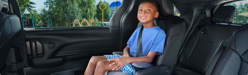 Child riding in a booster seat in the second row of a Toyota Sienna