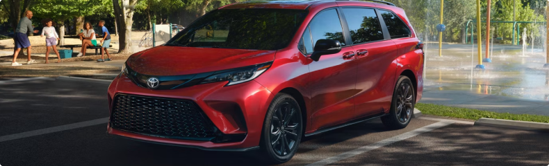Red Toyota Sienna parked beside a splash pad and picnic area