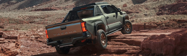 Green Toyota Tacoma climbing red rock, seen from the rear three-quarter