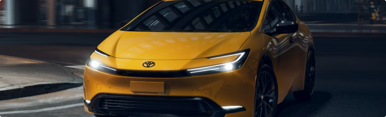 Yellow Toyota Prius at night on a city street, seen from the front