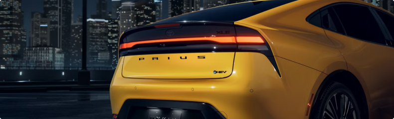 Rear detail of a yellow Toyota Prius showing the full-width tail lamp and Prius lettering